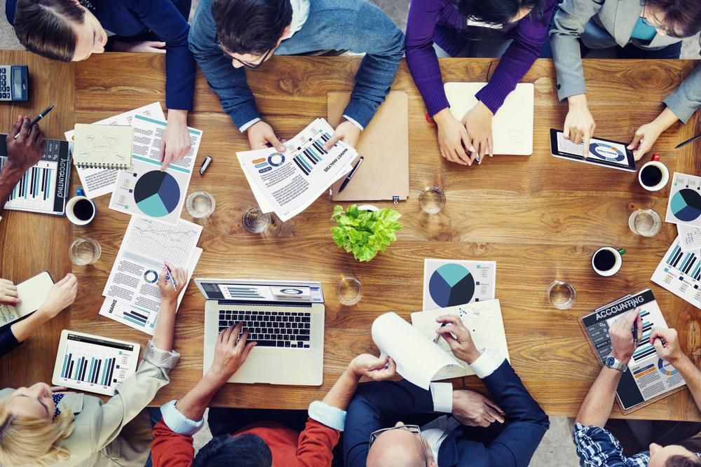 A Group of People Are Sitting Around a Table with Laptops and Papers — Sunshine Coast Financial Advisers in Mooloolaba, QLD
