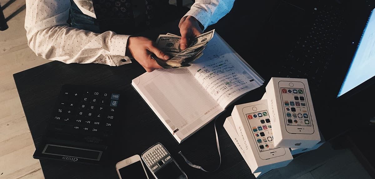 A Man Is Sitting at A Desk Counting Money — Sunshine Coast Financial Advisers in Maroochydore, QLD