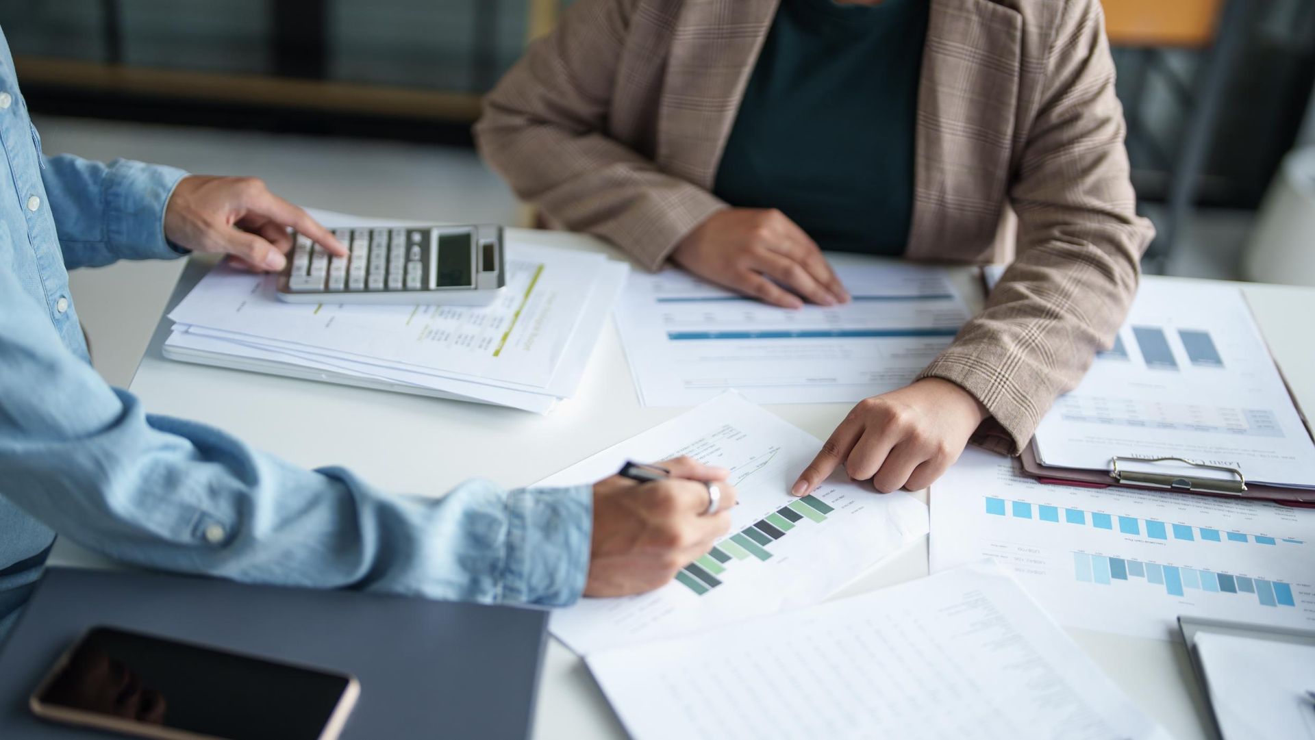 Two People Are Sitting at A Table with Papers and A Calculator — Sunshine Coast Financial Advisers in Mooloolaba, QLD