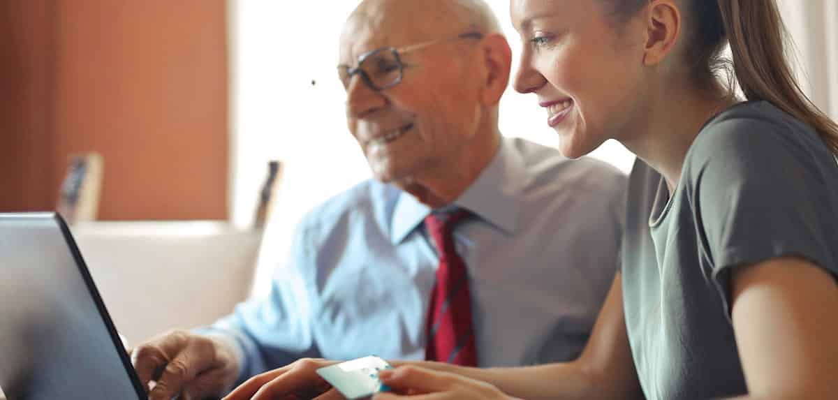 An Elderly Man and A Young Woman Are Looking at A Laptop Together — Sunshine Coast Financial Advisers in Maroochydore, QLD