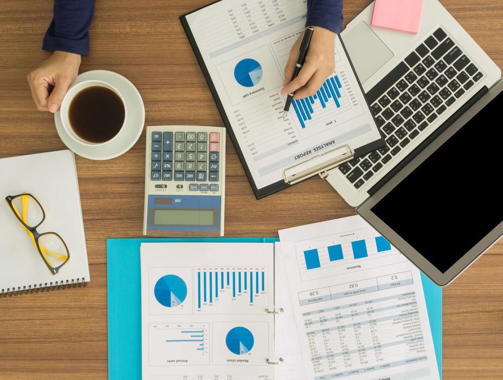 A Person Is Sitting at A Desk with A Laptop and A Cup of Coffee — Sunshine Coast Financial Advisers in Maroochydore, QLD