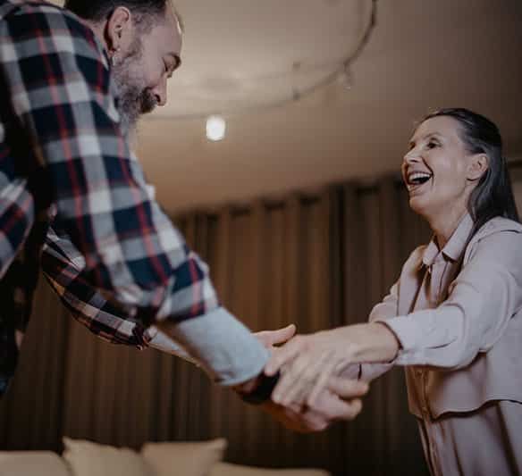 A Man and A Woman Are Shaking Hands in A Living Room — Sunshine Coast Financial Advisers in Maroochydore, QLD