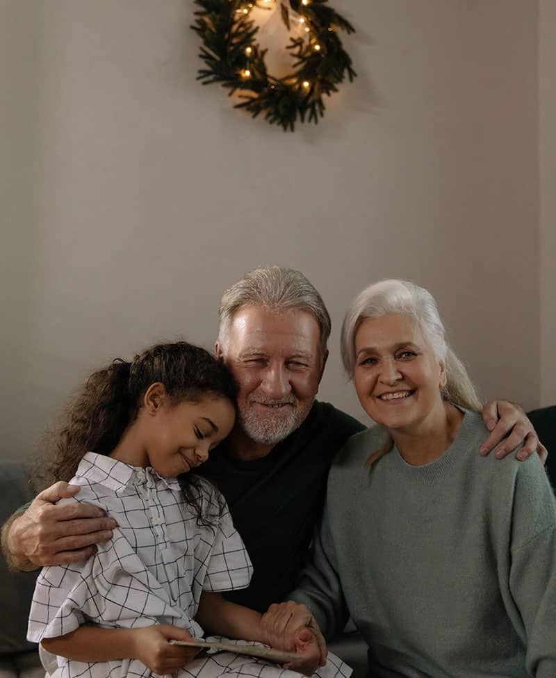 A Man and Two Women Are Sitting on A Couch with A Little Girl — Sunshine Coast Financial Advisers in Maroochydore, QLD