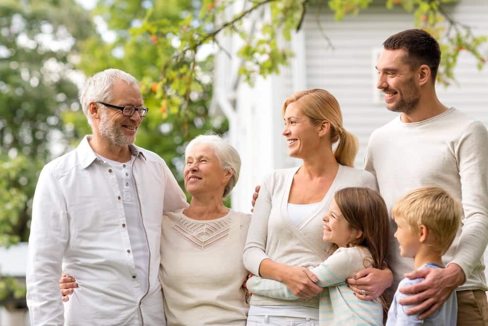 A Large Family Is Standing Next to Each Other in Front of A House — Sunshine Coast Financial Advisers in Maroochydore, QLD