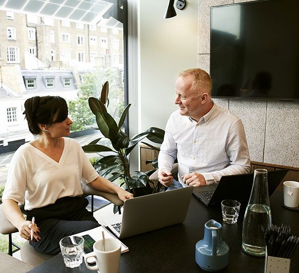 A Man and A Woman Are Sitting at A Table with A Laptop — Sunshine Coast Financial Advisers in Maroochydore, QLD