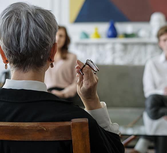 A Woman Is Sitting in A Chair Holding a Pair of Glasses — Sunshine Coast Financial Advisers in Maroochydore, QLD