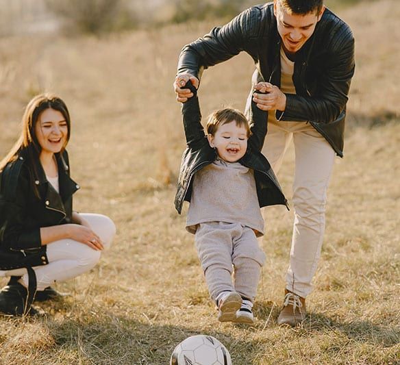 A Family Is Playing with A Soccer Ball in A Field — Sunshine Coast Financial Advisers in Maroochydore, QLD