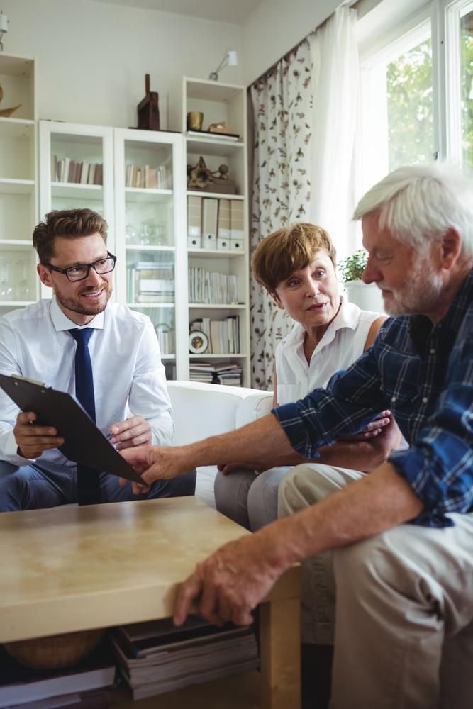A Man Is Holding a Clipboard While Talking to An Elderly Couple in A Living Room
