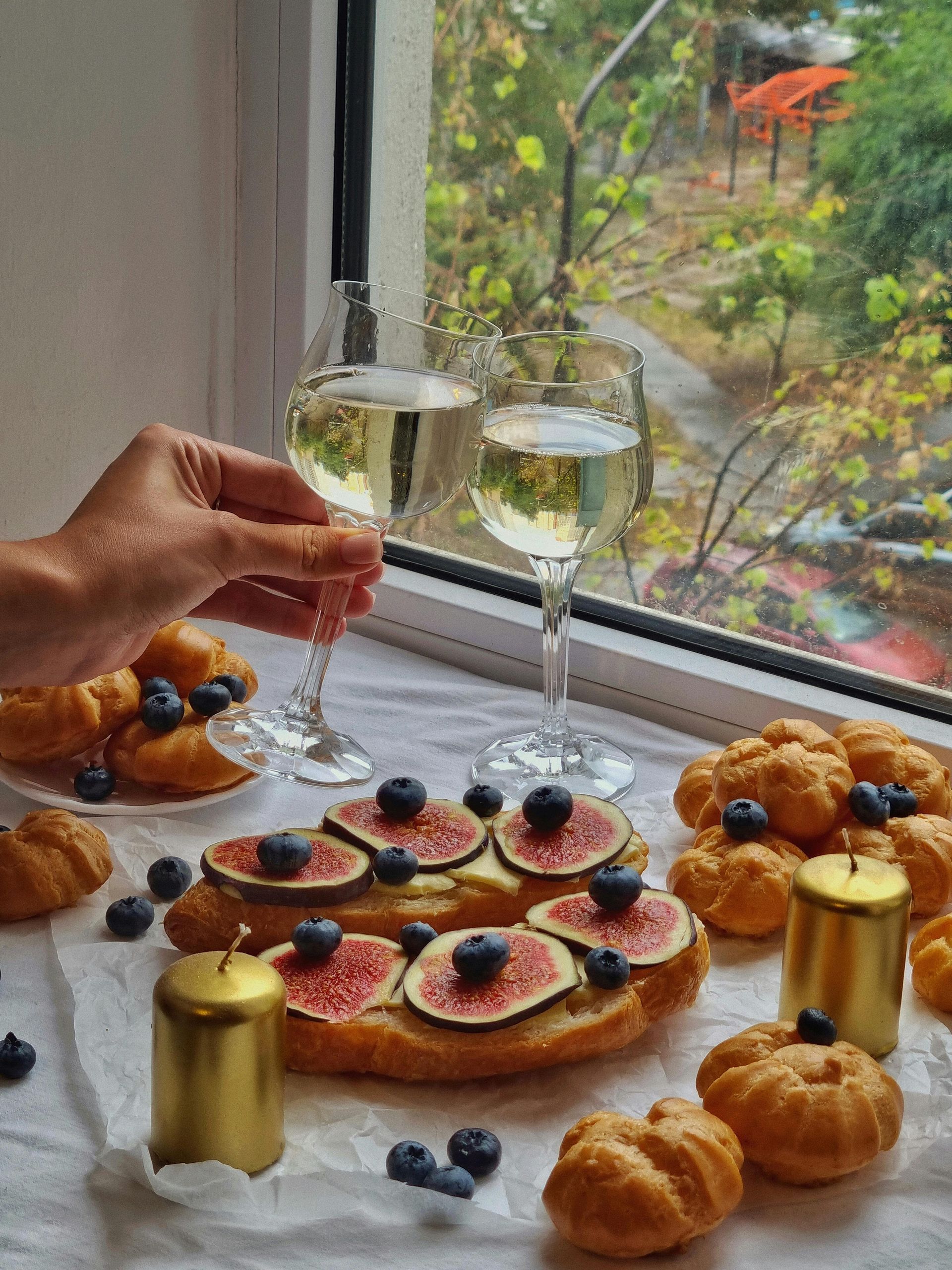 A person is holding a glass of wine in front of a window.