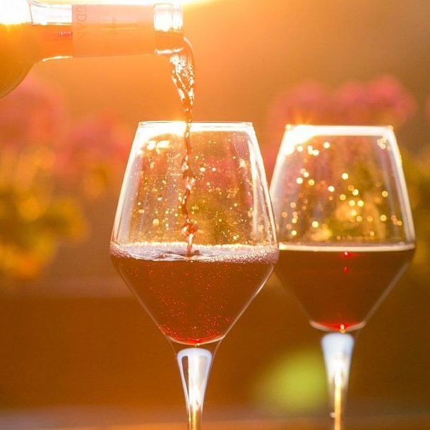 A bottle of wine is being poured into two wine glasses.