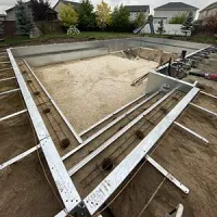 An in-ground swimming pool under construction with metal wall panels installed in a residential backyard.