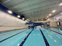 An indoor swimming pool with lap lanes and a large, blue spiral water slide in the background.