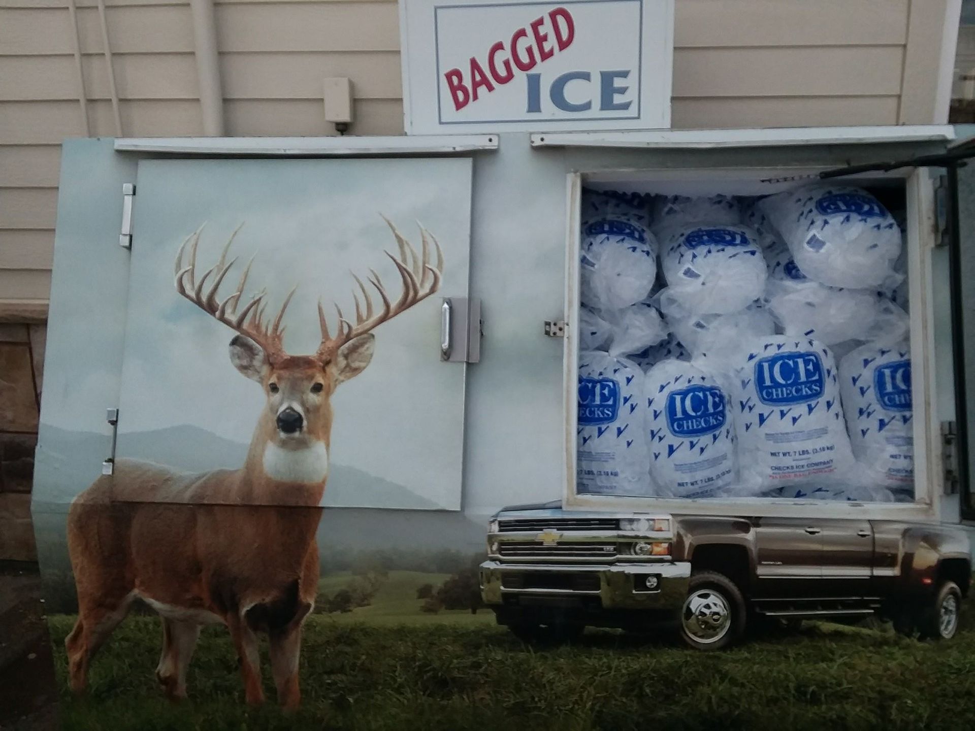 Bagged ice vending machine with deer graphic and bags of ice inside.