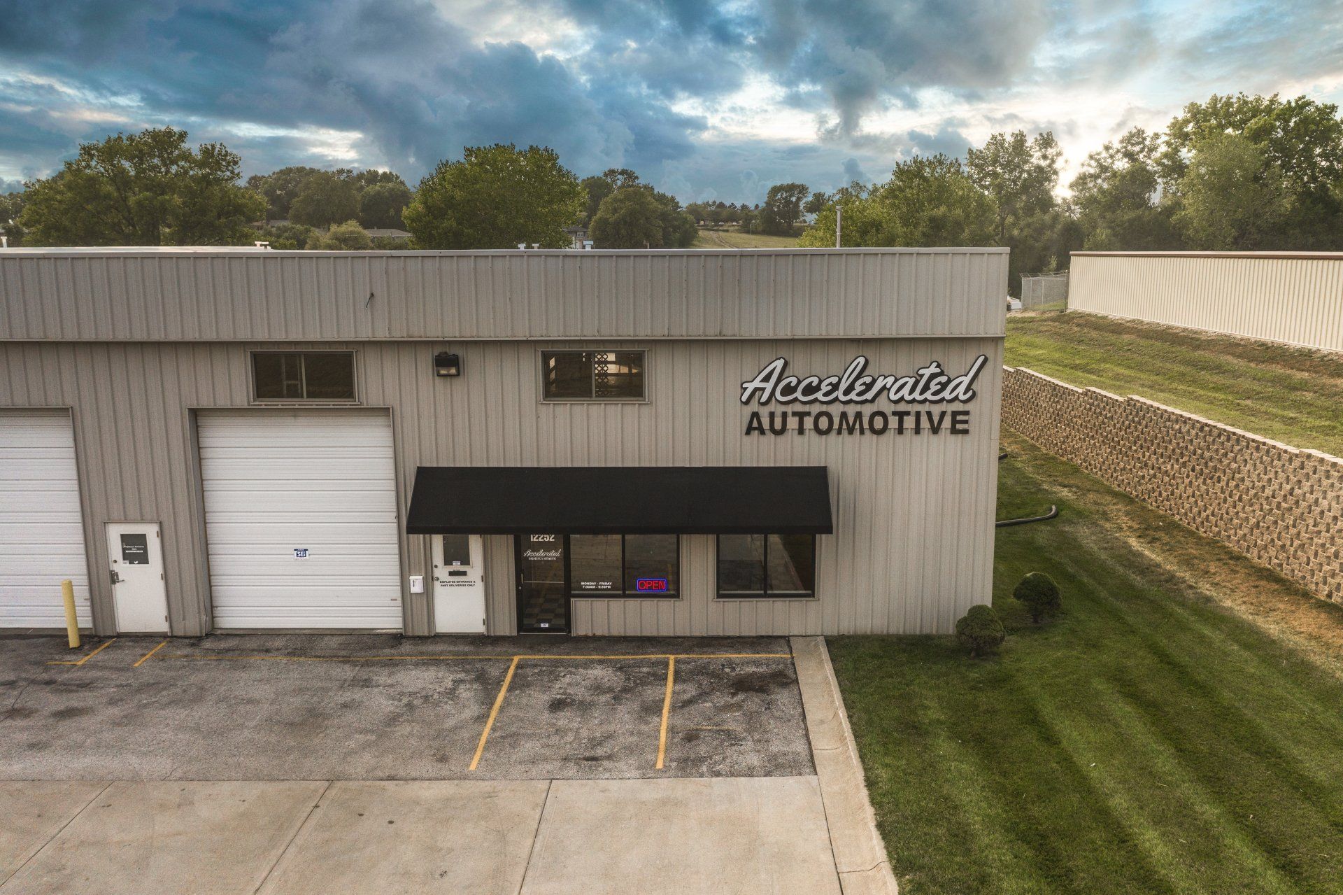 Exterior of Newland Automotive garage with white roll-up doors and black awning at sunset