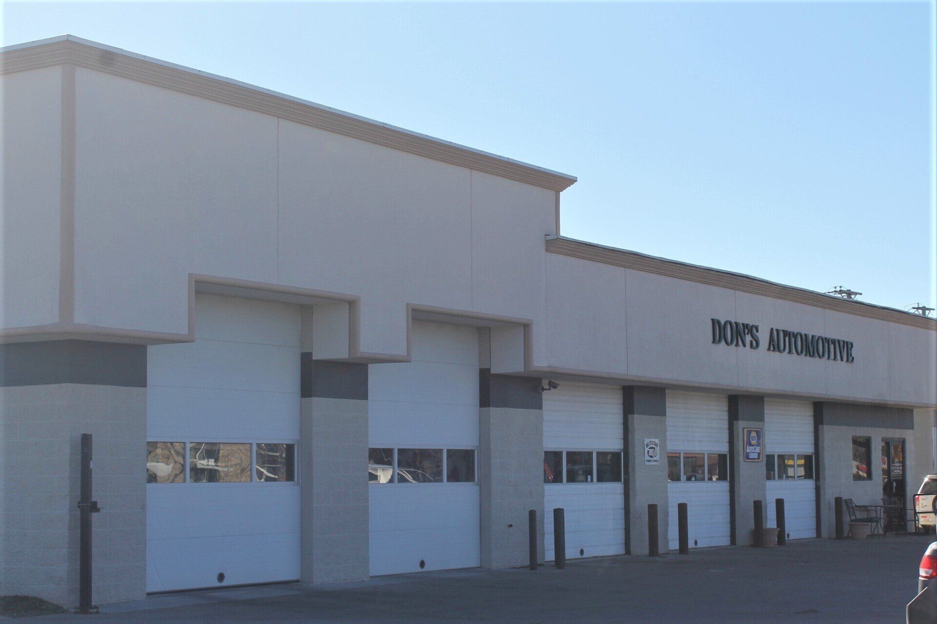 Exterior of a beige strip mall with large storefronts and a blue sky