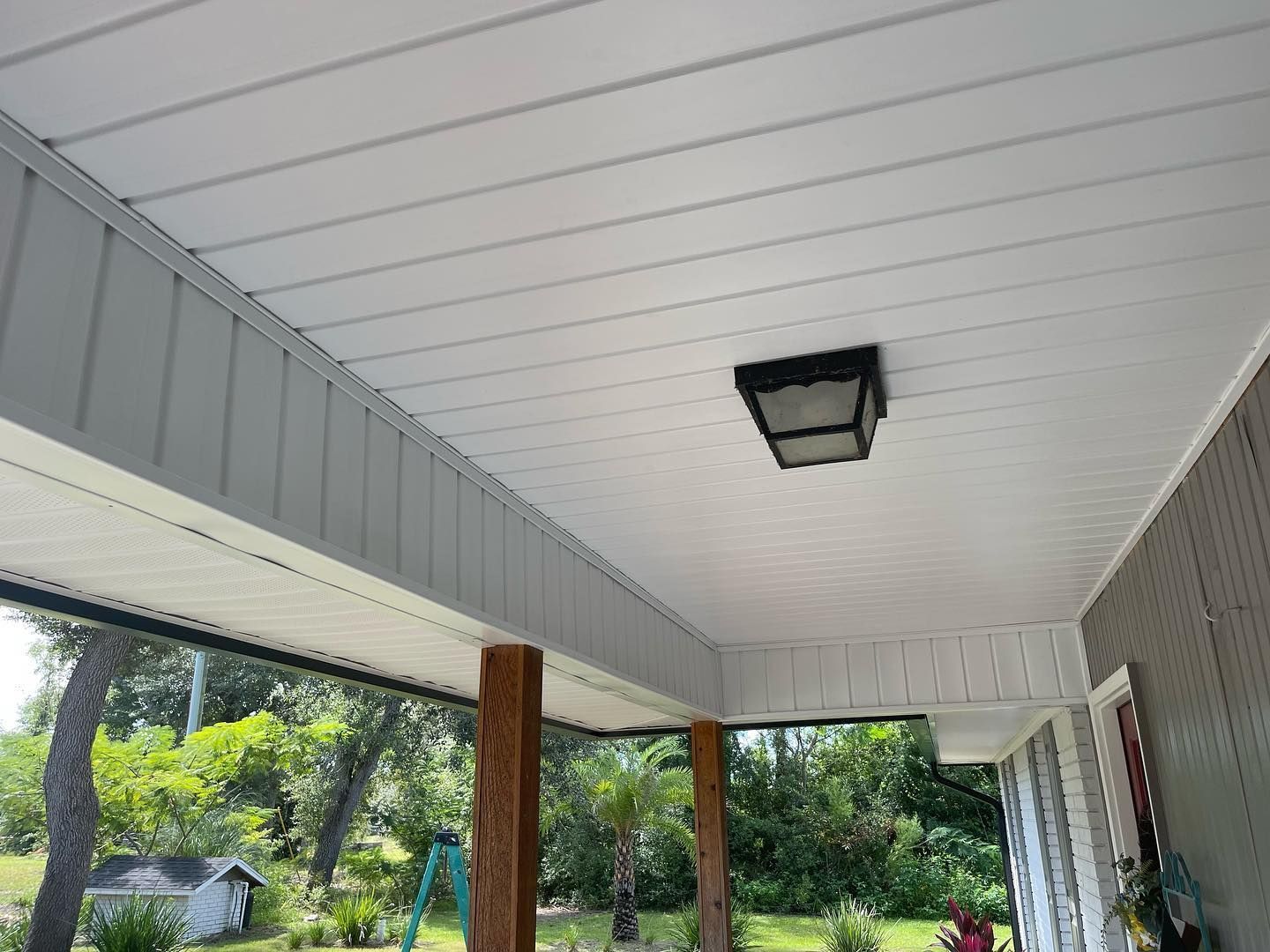 White ceiling with a square black light fixture and gray trim. Wooden post in foreground.