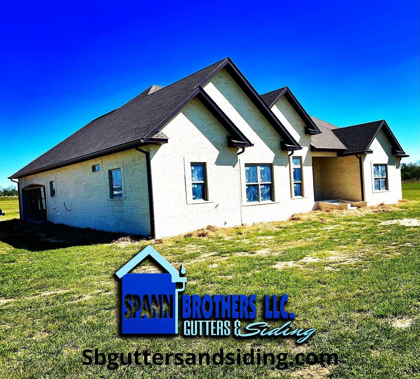 White brick house with dark roof under a blue sky, with 