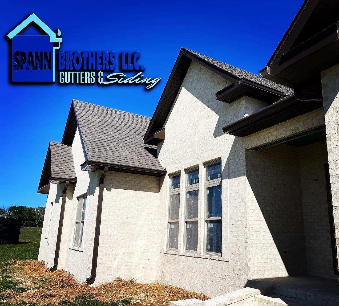 A beige house with brown gutters and roof, under a blue sky, by Spann Brothers LLC.