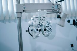 Foróptero de optometrista y equipo para examen ocular en una sala de consulta luminosa.