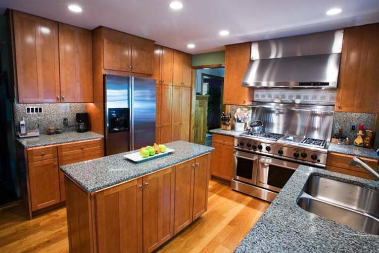 A spacious kitchen featuring wooden cabinetry, granite countertops, a center island, and stainless steel appliances.