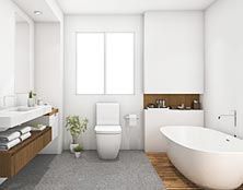 Modern white bathroom featuring a freestanding tub, floating wooden vanity, toilet, and a window against white walls.