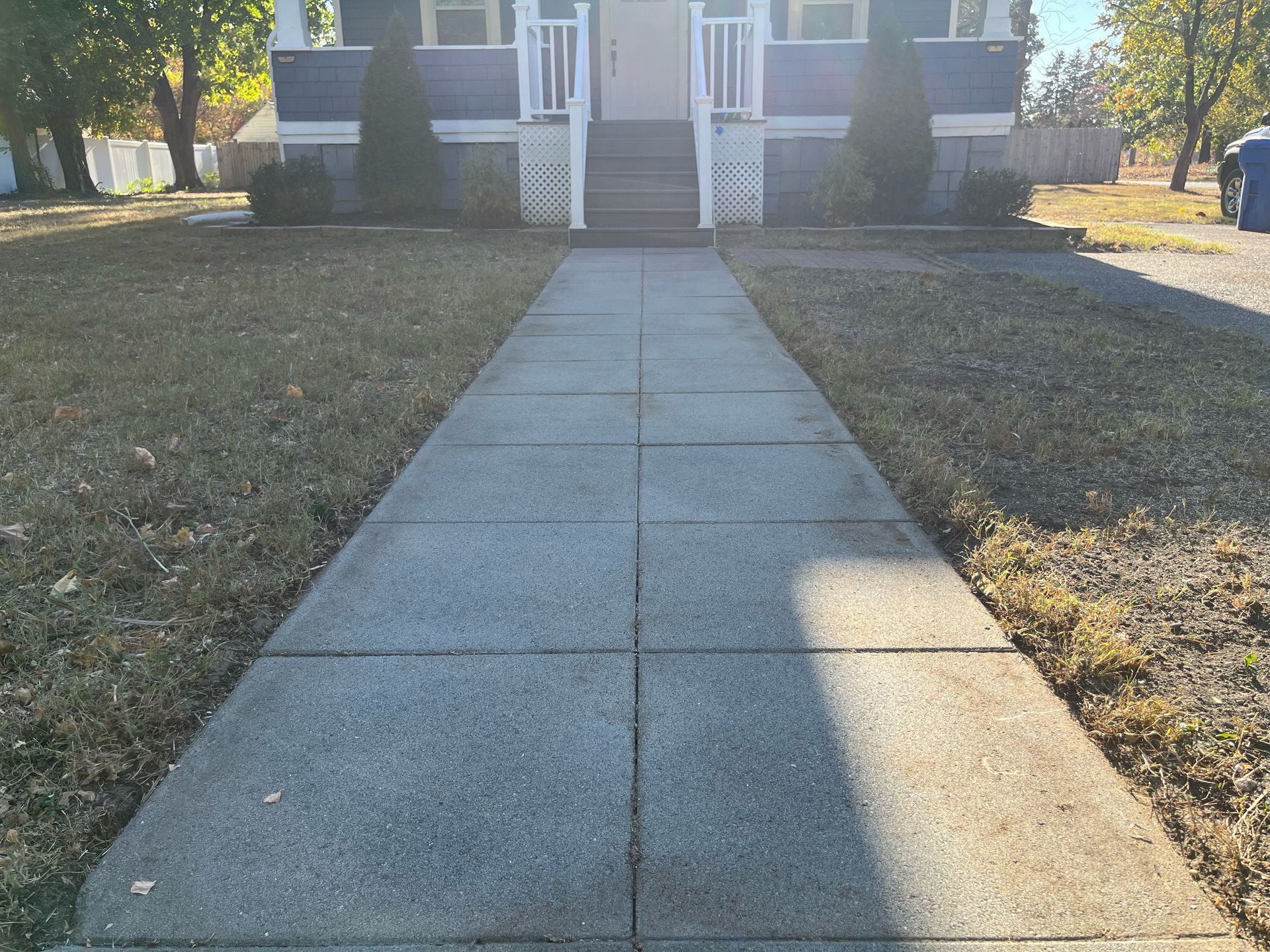 A concrete walkway leading to a blue house