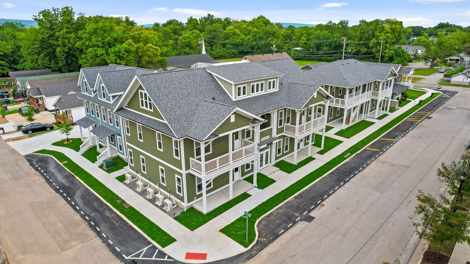 Two-story apartment buildings with white and yellow exteriors, each with a covered porch, sit along bailey avenue.