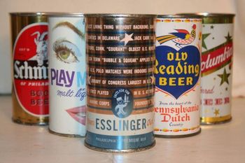 Assorted vintage beer cans arranged in a row on a table, featuring colorful labels and logos