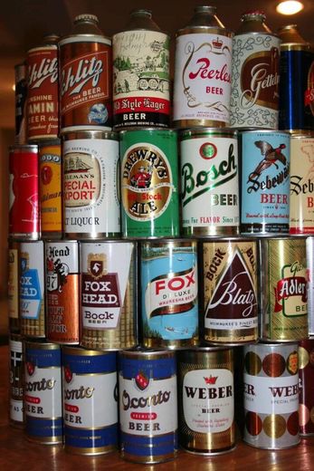 Stacked colorful vintage beer cans displayed on shelves indoors.