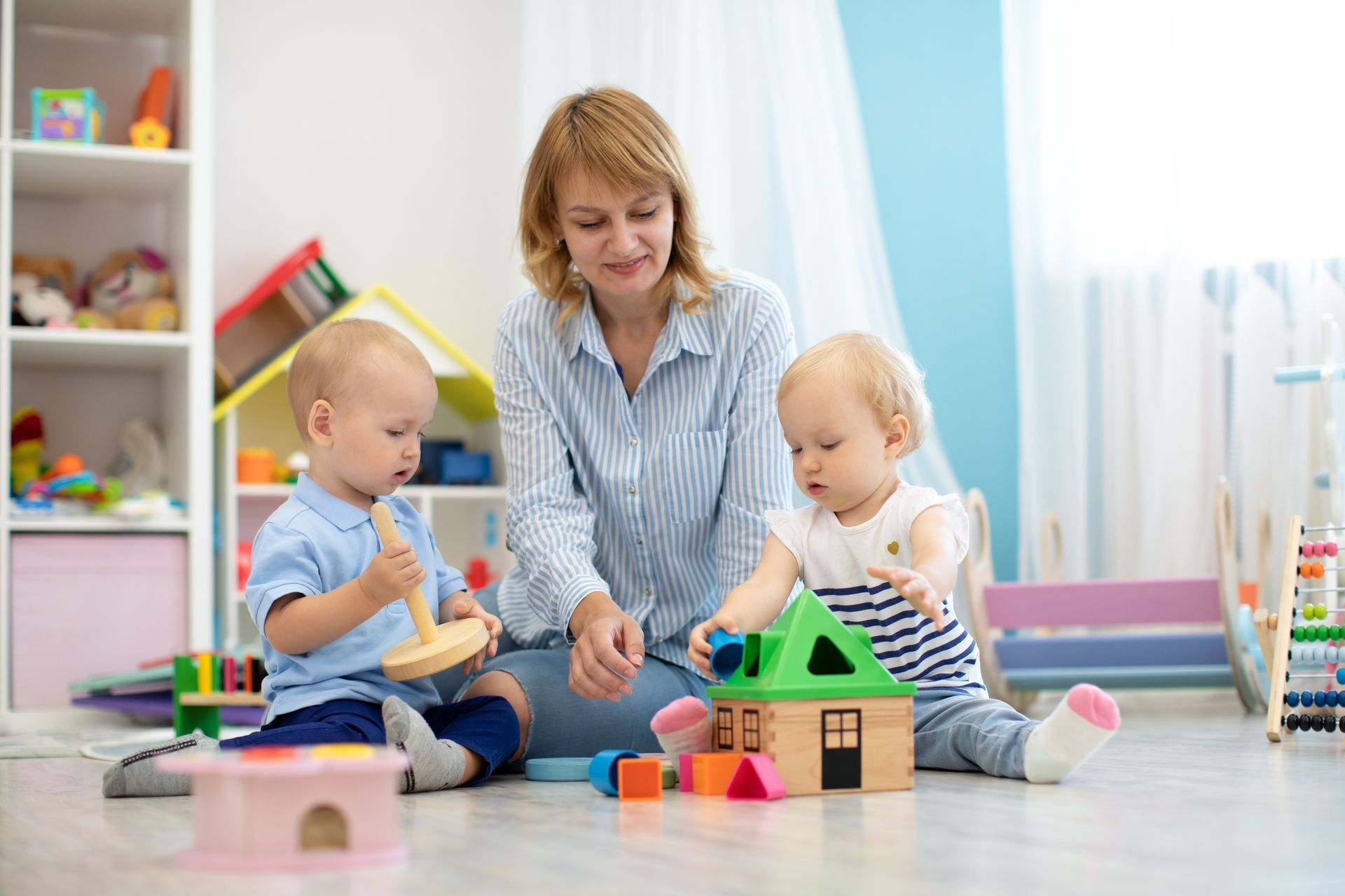 Children with teacher playing with educational toys in kindergarten