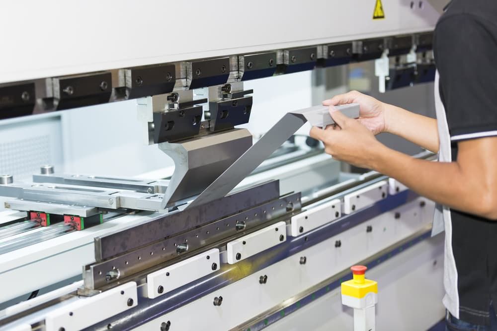 A Man Is Working On A Machine In A Factory - Gold Coast Laser And Pipe Bending in Mudgeeraba, QLD