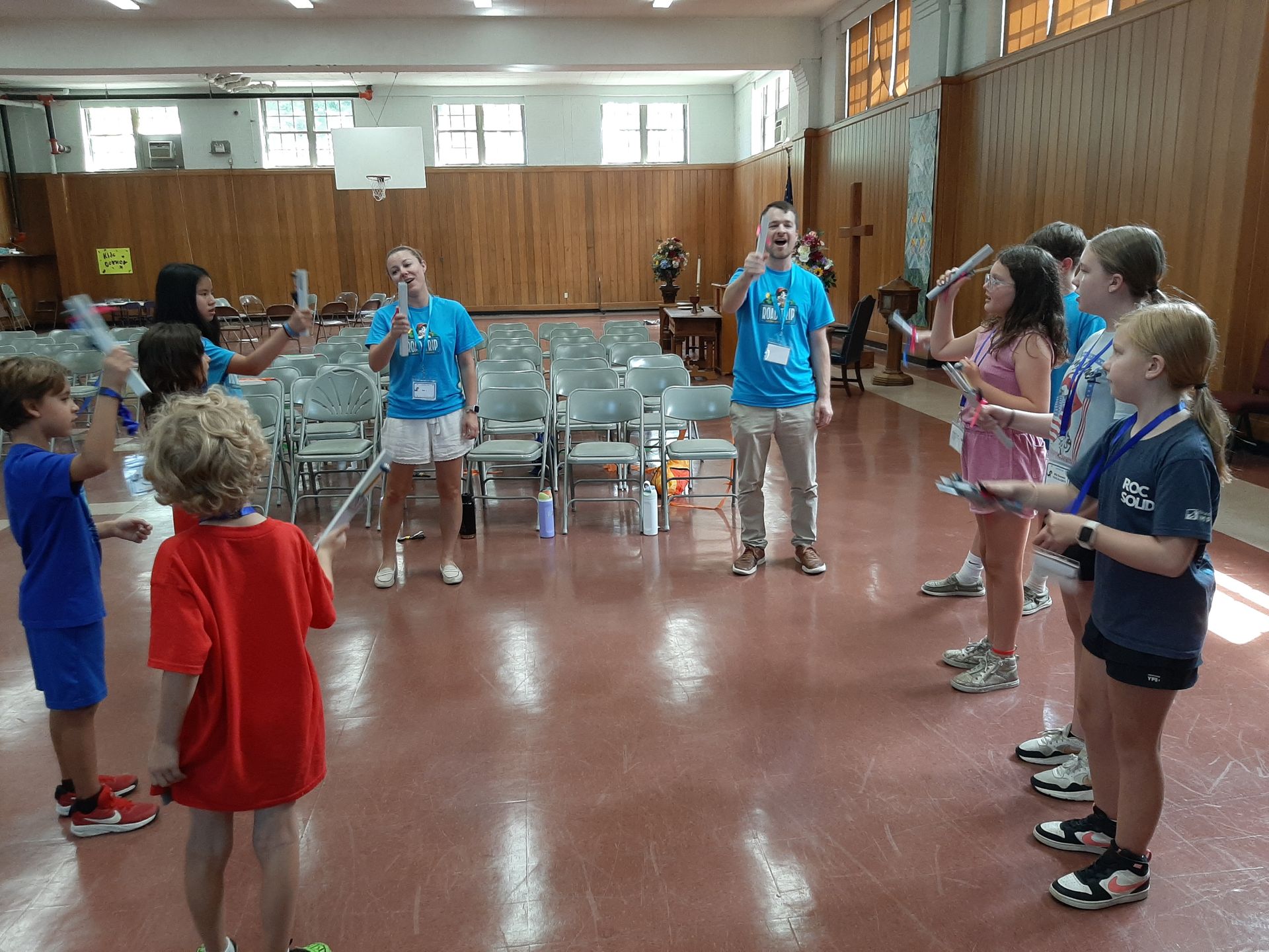 Children standing in a circle in a gymnasium during a group activity