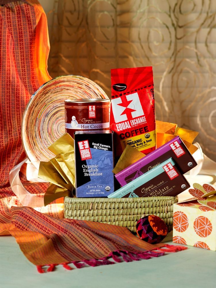 Assorted colorful snack packages arranged in a festive gift basket with woven mats and warm lighting