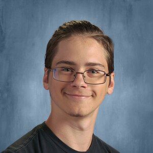 Portrait of a smiling person wearing glasses against a blue studio backdrop