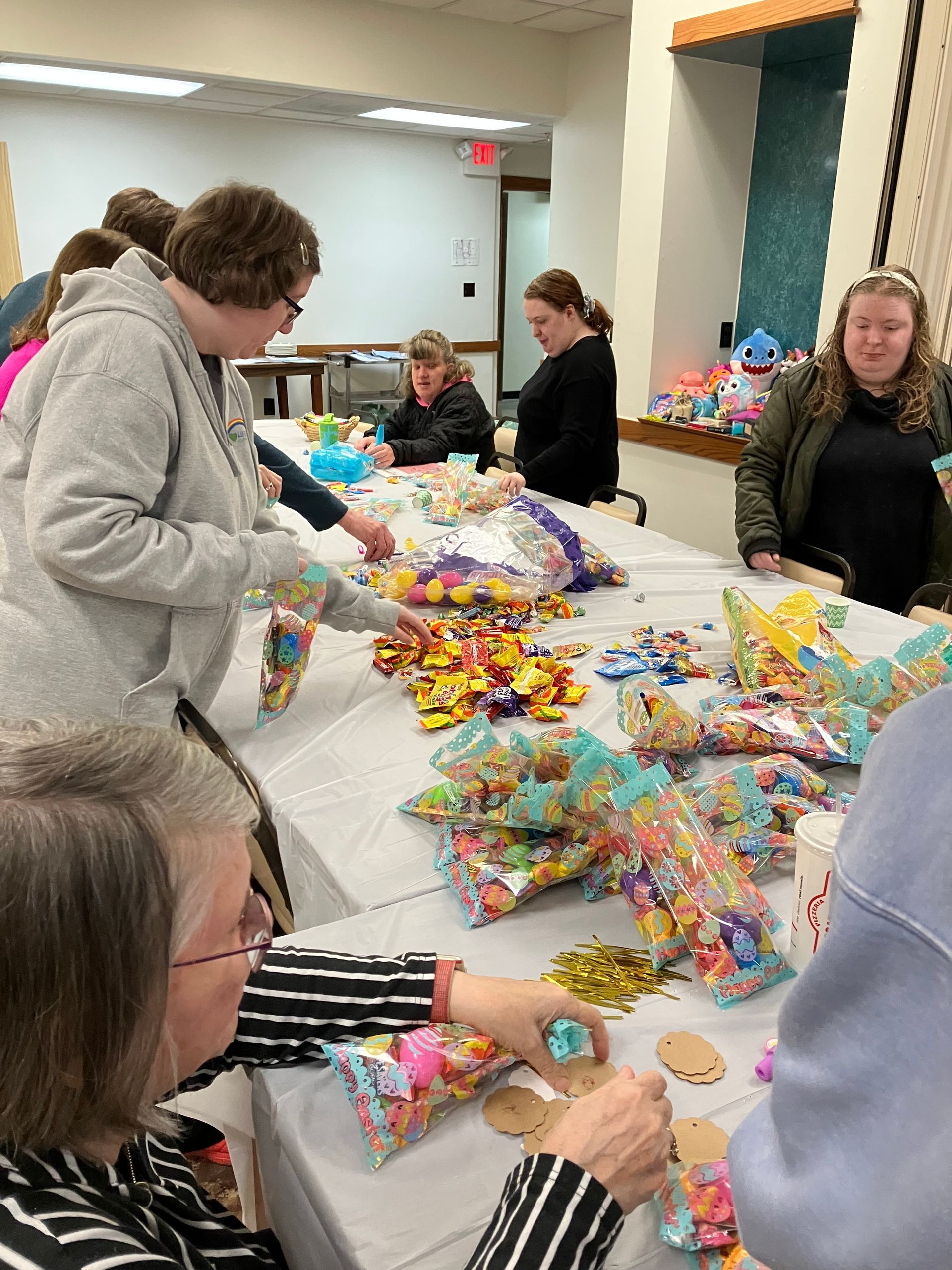 People sorting colorful wrapped candy and bags on a table in a room