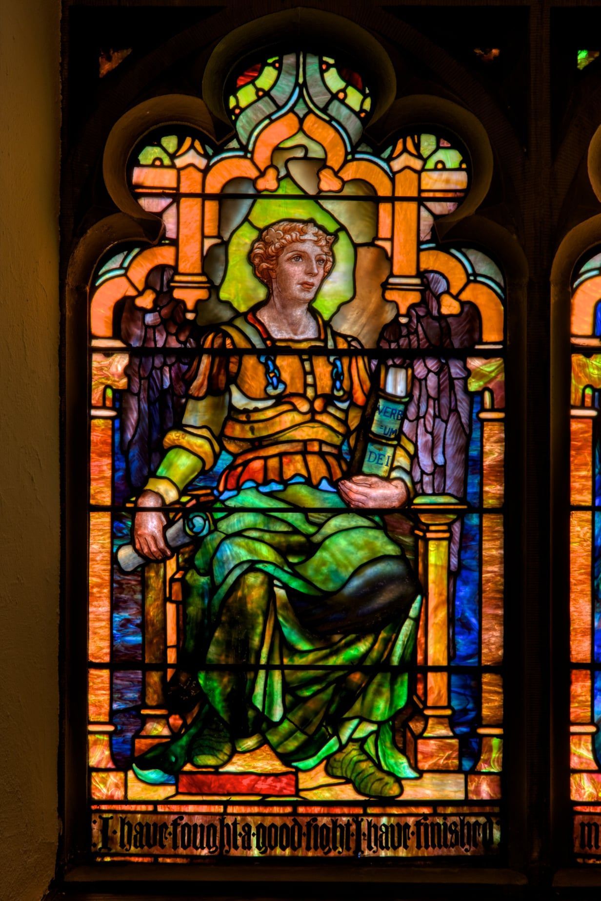 Stained glass window of a crowned figure seated on a throne, in green and gold robes.