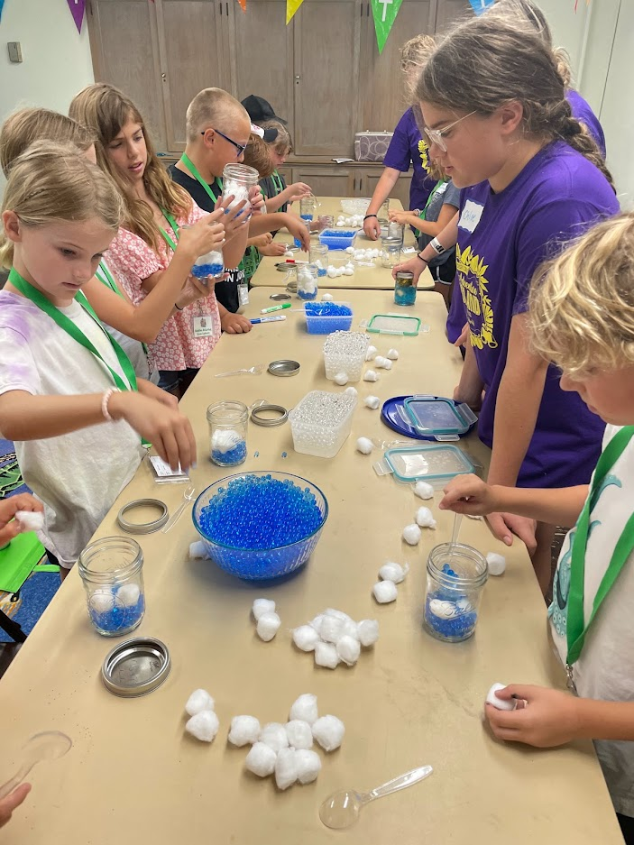 Children making blue-and-white crafts at a long table in a classroom or workshop