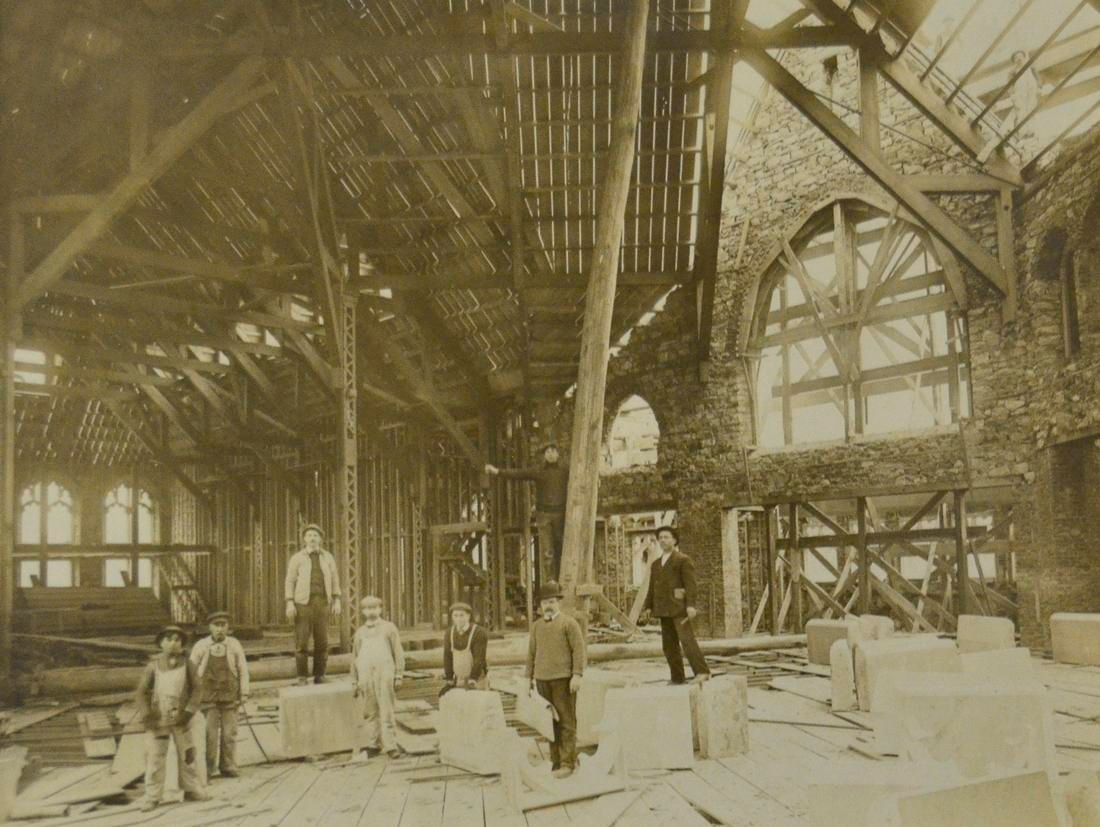 People in a large unfinished building with exposed steel beams and debris scattered around.