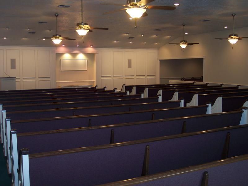 an empty church with purple benches and a ceiling fan