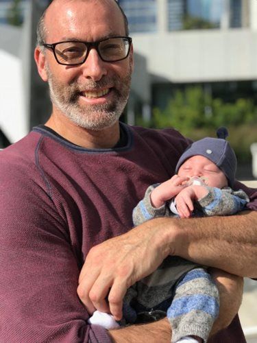 Dr. Michael Milobsky, pediatrician at Chicken Soup Concierge Pediatrics is holding a newborn baby