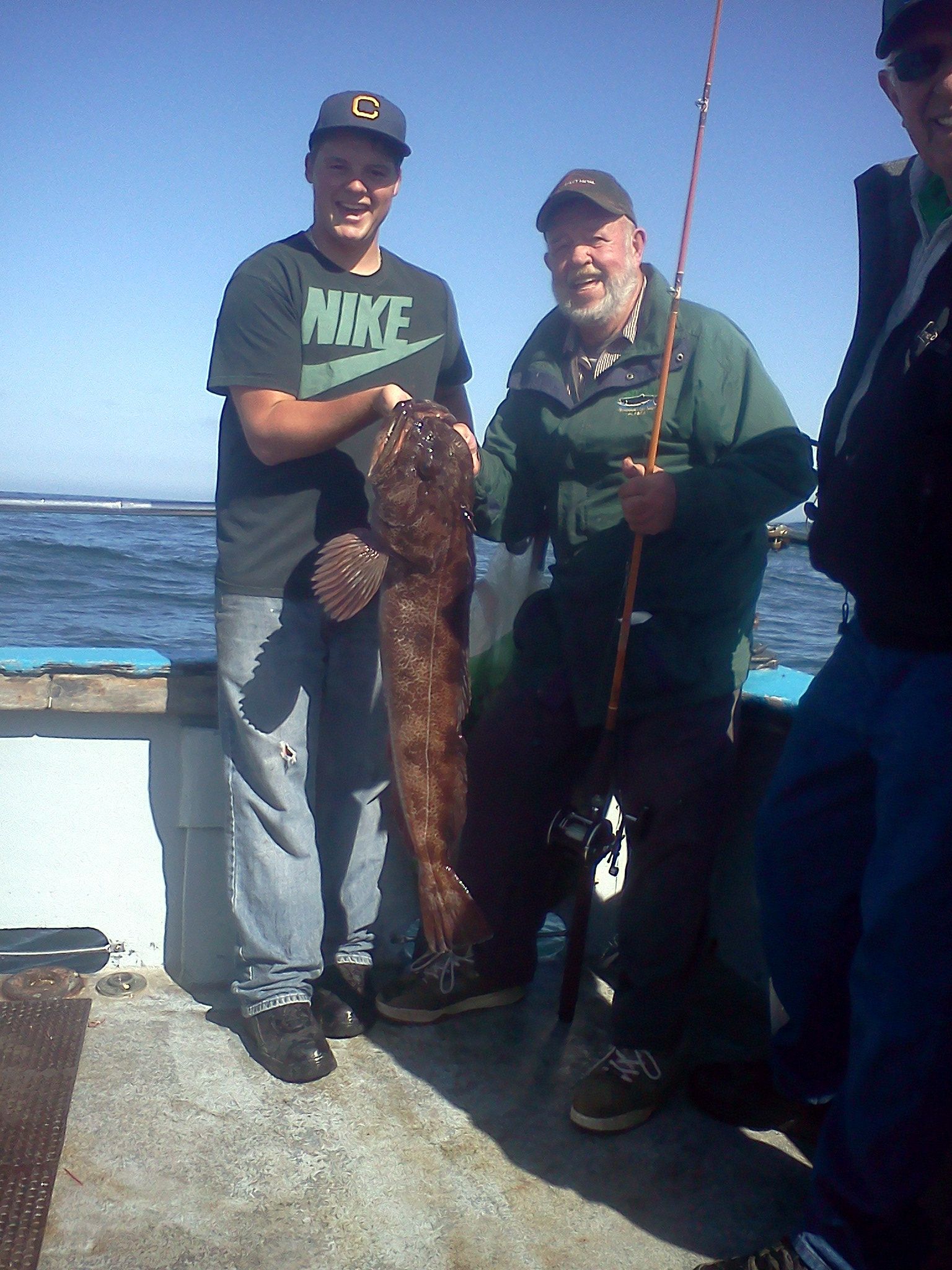 A man wearing a nike shirt is holding a large fish