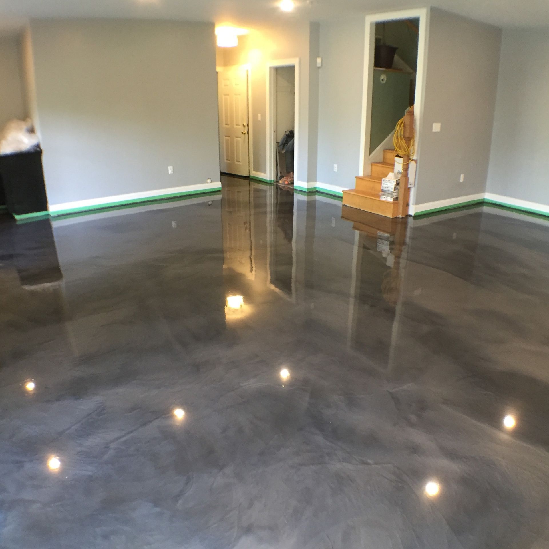 Empty living room with glossy dark floor, gray walls, and open doorways.