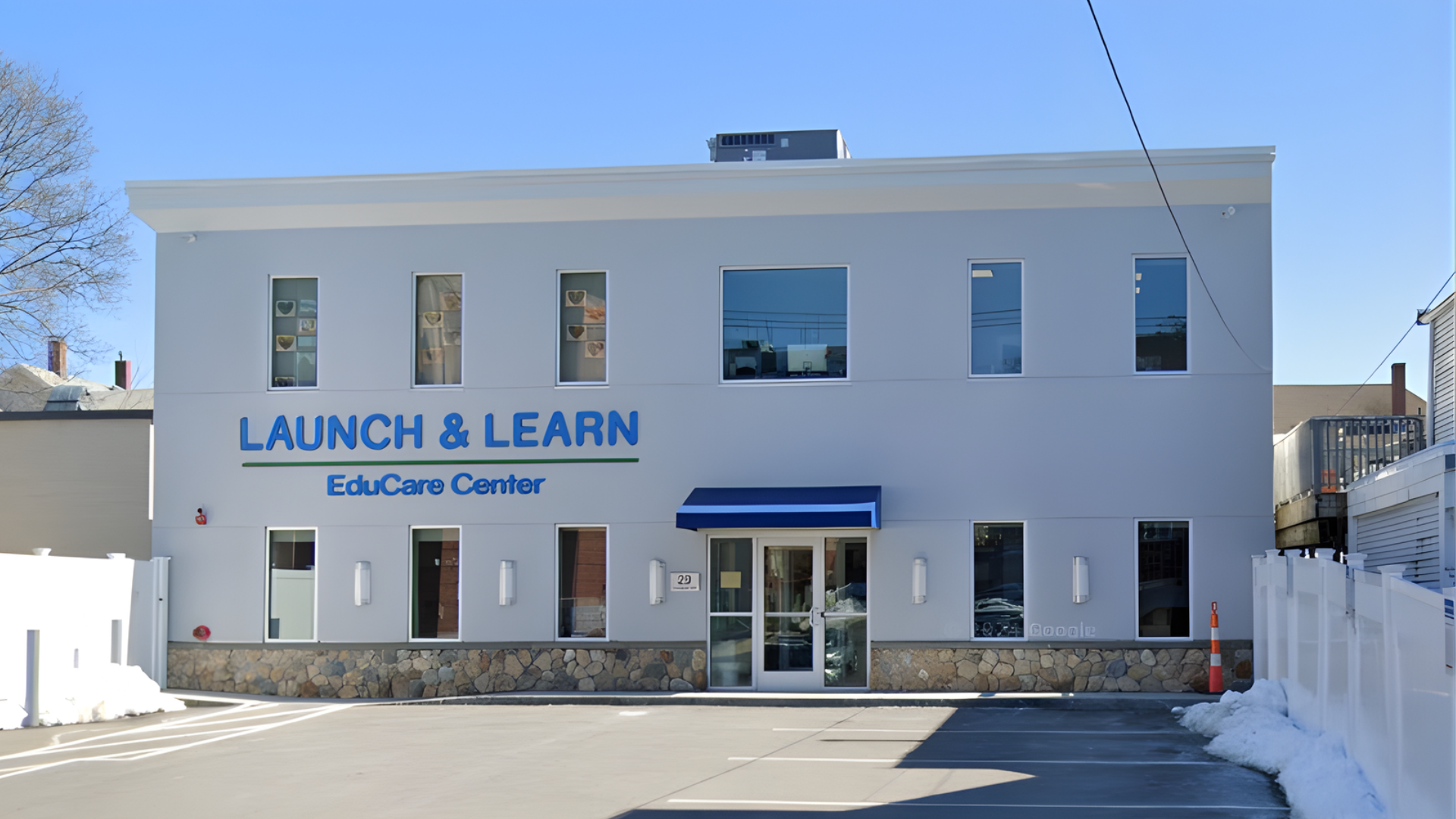 Launch & Learn EduCare Center, a two-story light gray building with blue awning and signage.
