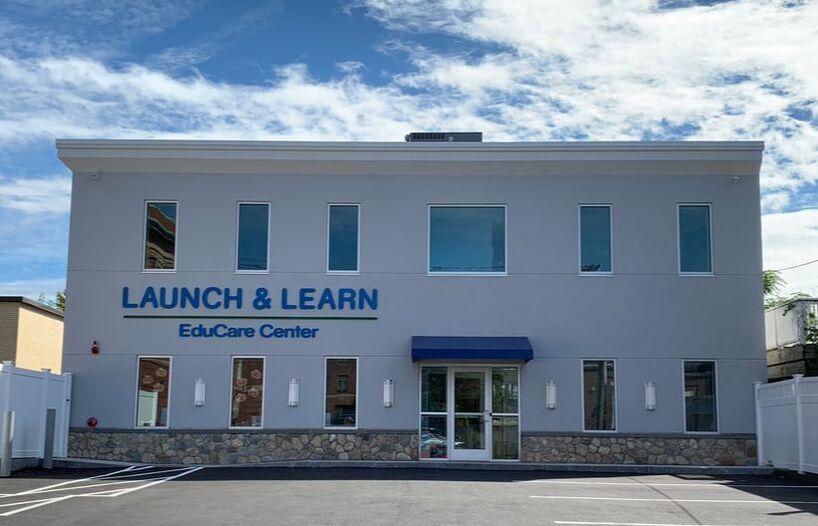 Launch & Learn EduCare Center, a two-story light gray building with blue awning and signage.