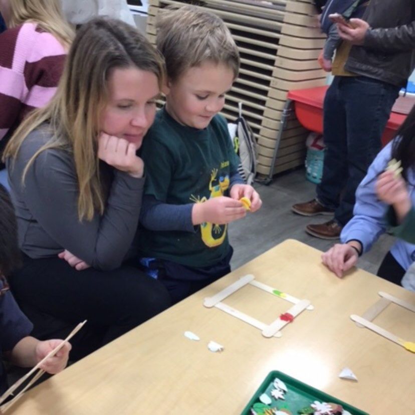 Woman and child looking at a craft project on a table.