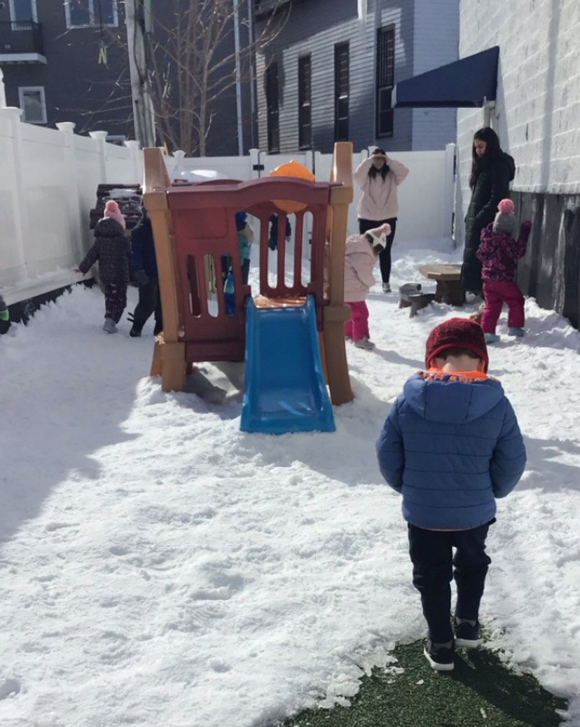 Children playing in snowy playground with slide. Adult supervision.