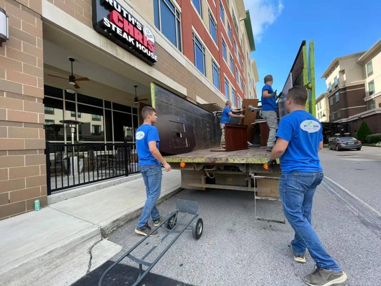 Two men are loading furniture onto a truck in front of a building.
