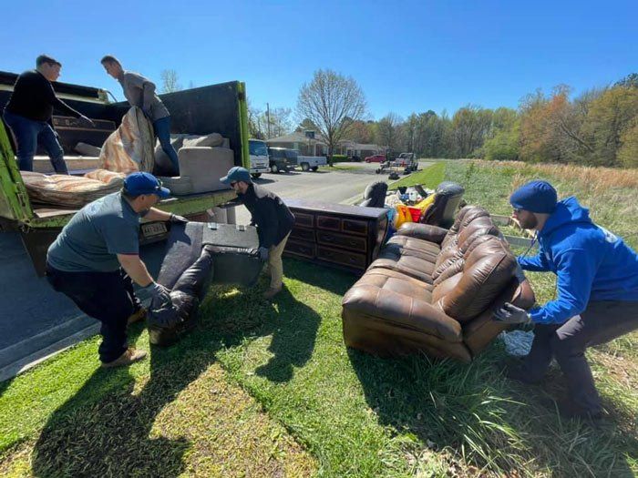 A group of people are moving furniture in a field.