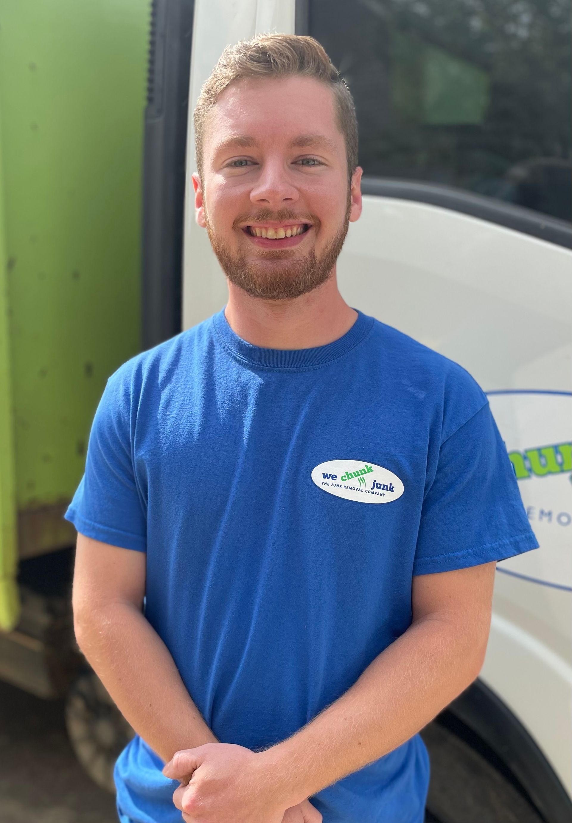 A man in a blue shirt is standing in front of a white truck.