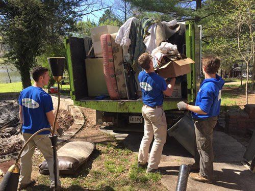 A group of men in blue shirts are loading a moving truck.